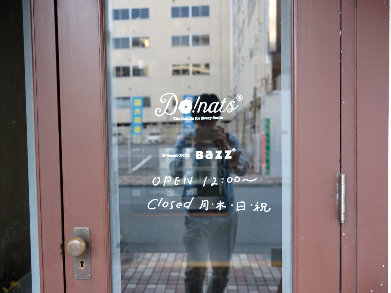 甲府市の桜町通りにあるcafe-do!natusの入り口のドアに開店時間と開店曜日が記載してある